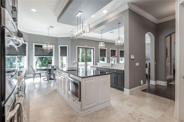 kitchen with a wealth of natural light, built in microwave, a kitchen island with sink, sink, and pendant lighting