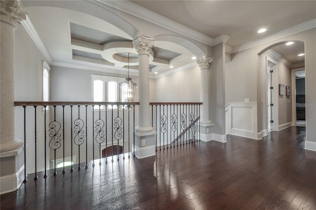 hallway featuring dark wood-type flooring, an inviting chandelier, ornamental molding, decorative columns, and coffered ceiling