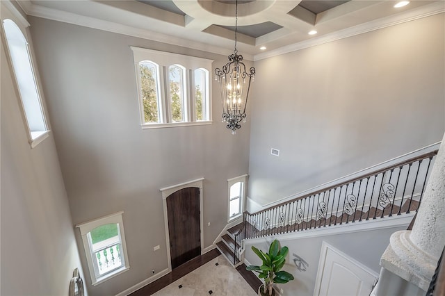 entryway featuring coffered ceiling, crown molding, plenty of natural light, and a towering ceiling