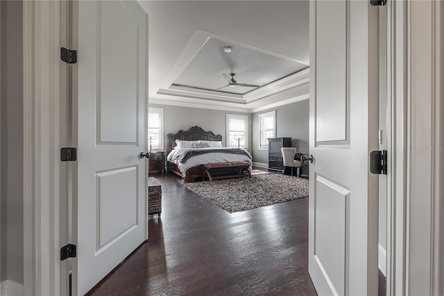 bedroom with crown molding, dark hardwood / wood-style floors, and a tray ceiling