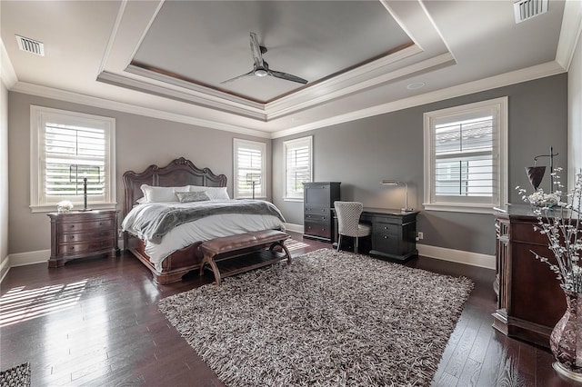 bedroom with crown molding, dark hardwood / wood-style floors, a tray ceiling, and ceiling fan