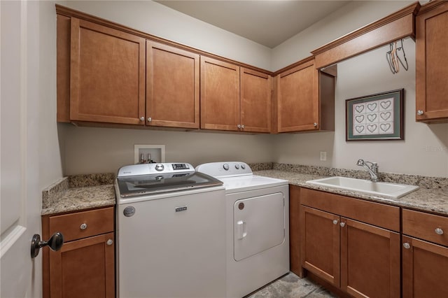 clothes washing area featuring sink, washer and clothes dryer, and cabinets