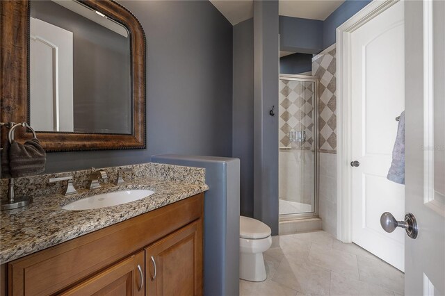 bathroom featuring vanity, toilet, a shower with door, and tile patterned flooring