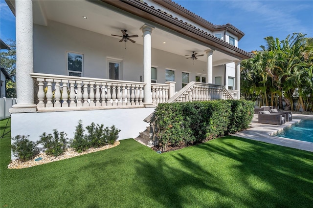 rear view of house featuring ceiling fan, a fenced in pool, and a lawn