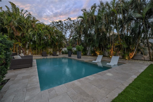 pool at dusk with a patio area