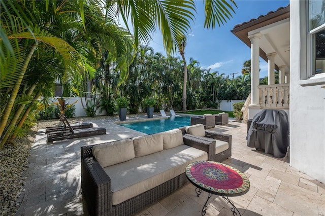 view of pool with an outdoor living space, a patio area, and a grill