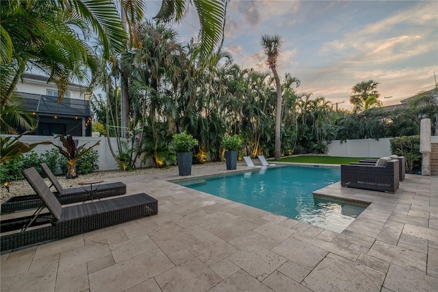 pool at dusk featuring a patio area