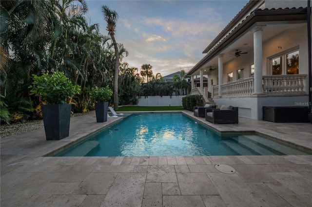 pool at dusk featuring a patio area and ceiling fan