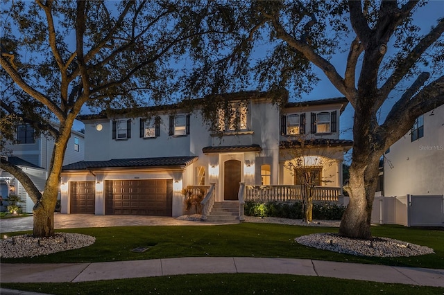 mediterranean / spanish home with a garage and a front lawn