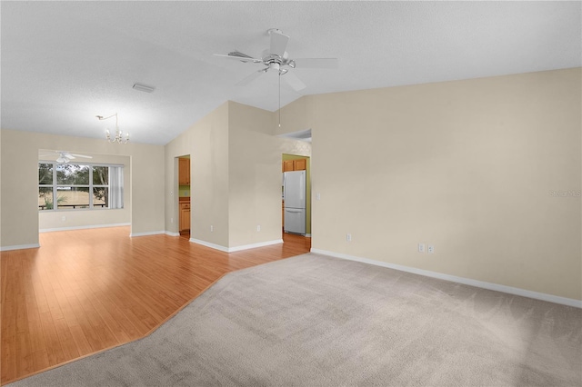 unfurnished room with ceiling fan with notable chandelier, vaulted ceiling, light hardwood / wood-style flooring, and a textured ceiling