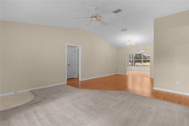 empty room featuring light colored carpet, lofted ceiling, and ceiling fan with notable chandelier