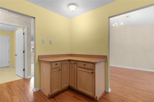 kitchen with pendant lighting, a notable chandelier, a textured ceiling, and light hardwood / wood-style flooring