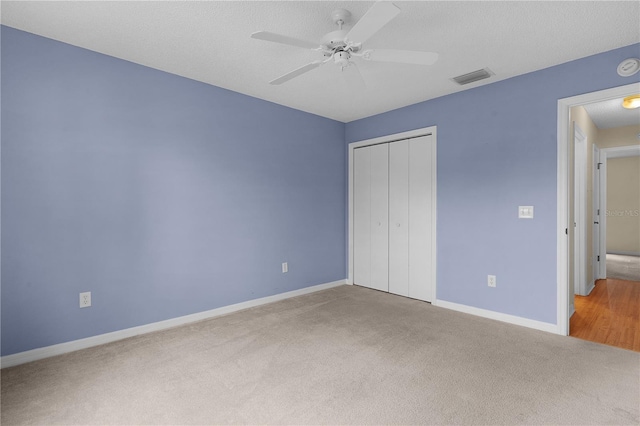 unfurnished bedroom featuring a textured ceiling, a closet, ceiling fan, and carpet