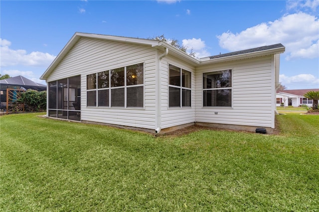 back of property featuring a sunroom and a lawn