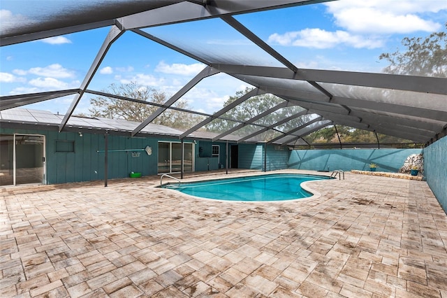 view of swimming pool featuring glass enclosure and a patio area