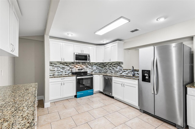 kitchen with sink, appliances with stainless steel finishes, white cabinets, light stone countertops, and backsplash