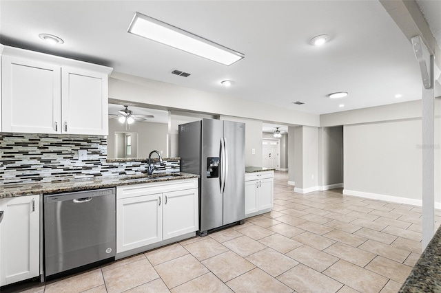 kitchen featuring sink, white cabinetry, tasteful backsplash, dark stone counters, and stainless steel appliances