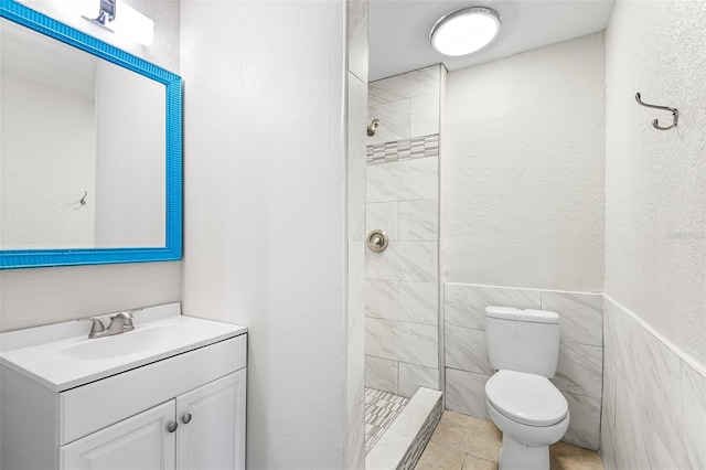 bathroom featuring tile walls, tile patterned flooring, vanity, tiled shower, and toilet