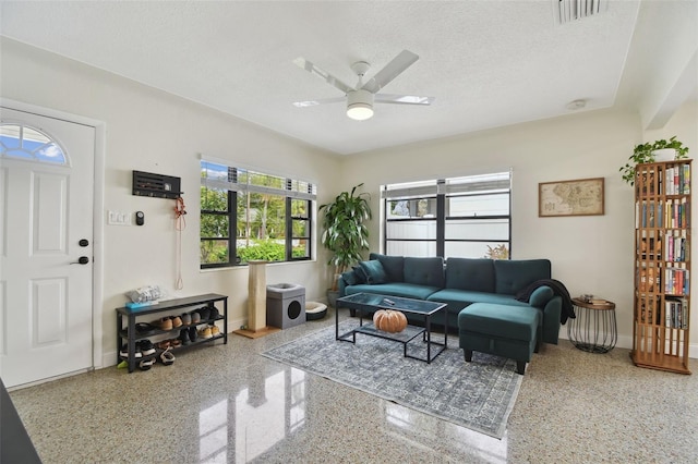 living room with ceiling fan and a textured ceiling