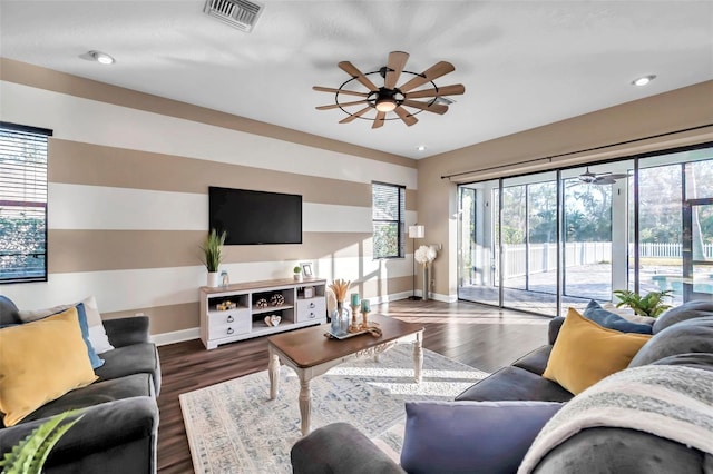 living room with dark wood-style floors, visible vents, ceiling fan, and baseboards