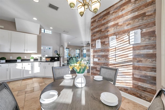 dining area featuring arched walkways, stone tile flooring, visible vents, and wooden walls