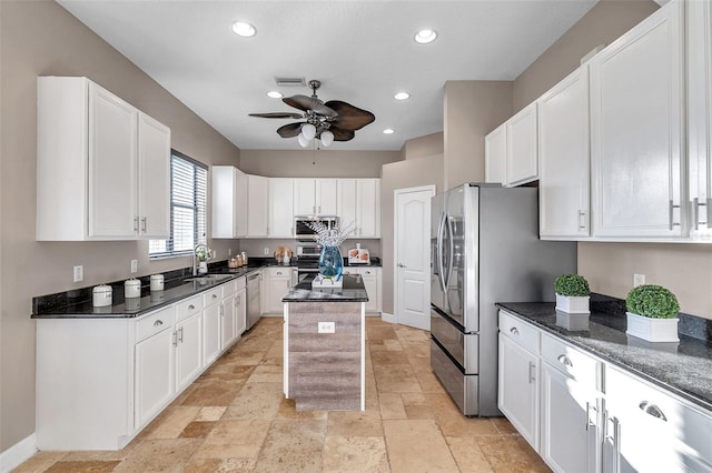 kitchen featuring stainless steel appliances, visible vents, white cabinets, a kitchen island, and dark stone countertops