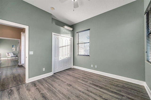 unfurnished bedroom with a closet, dark wood finished floors, and baseboards