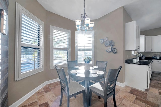 dining room featuring baseboards, a chandelier, and stone tile flooring