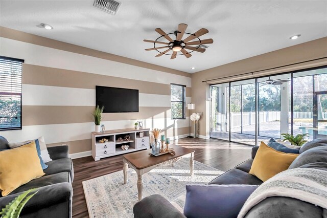 living area with visible vents, baseboards, a ceiling fan, and wood finished floors
