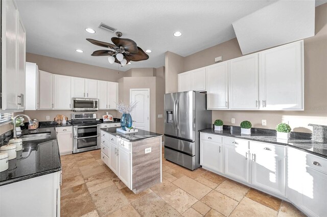 kitchen with appliances with stainless steel finishes, visible vents, ceiling fan, stone tile floors, and a sink