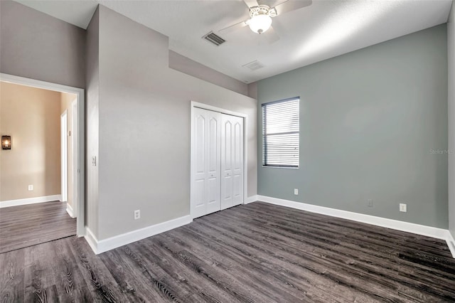 unfurnished bedroom with dark wood-style flooring, a closet, baseboards, a ceiling fan, and visible vents