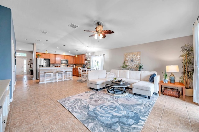 tiled living room featuring ceiling fan with notable chandelier