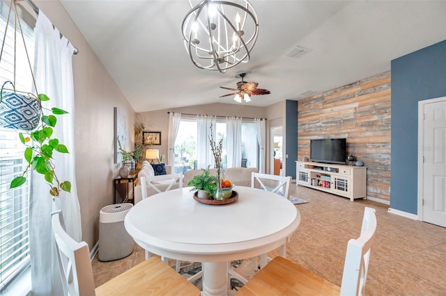 tiled dining space with ceiling fan with notable chandelier and vaulted ceiling