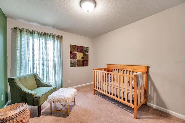 bedroom featuring carpet floors, a textured ceiling, and a crib