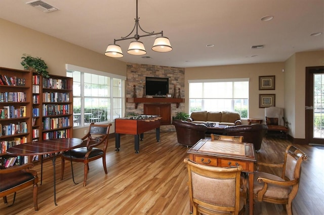 dining room featuring a stone fireplace and light hardwood / wood-style flooring