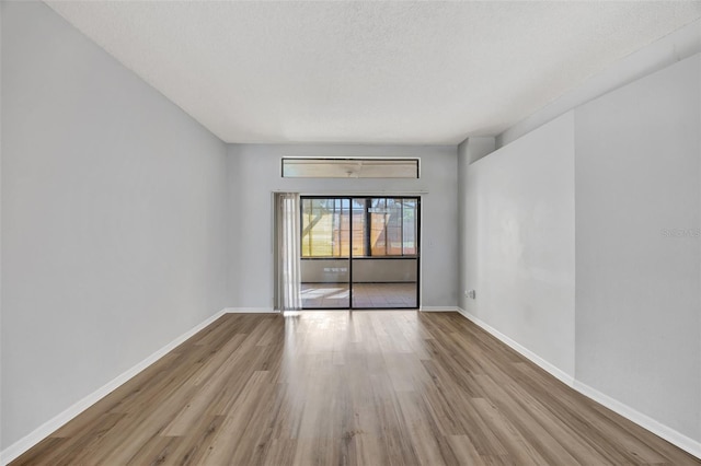 unfurnished room with a textured ceiling and light hardwood / wood-style floors