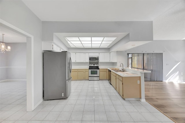 kitchen featuring sink, an inviting chandelier, light tile patterned floors, kitchen peninsula, and stainless steel appliances