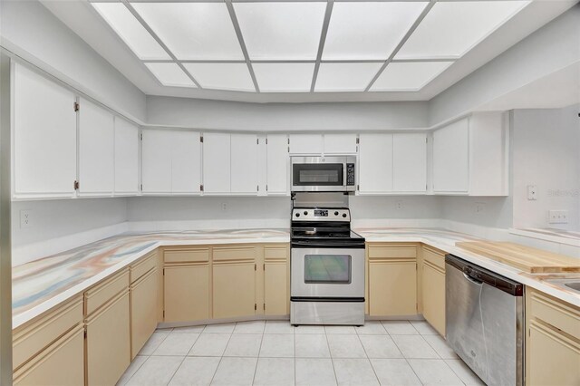 kitchen featuring stainless steel appliances, light tile patterned flooring, and cream cabinets