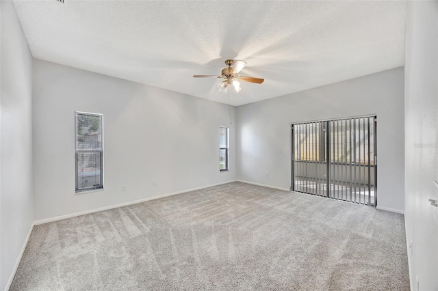 unfurnished room featuring ceiling fan, light colored carpet, and a textured ceiling