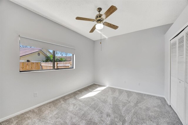 unfurnished bedroom featuring a textured ceiling, a closet, ceiling fan, and carpet