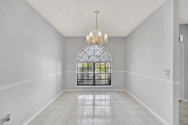 tiled empty room featuring a chandelier and a textured ceiling