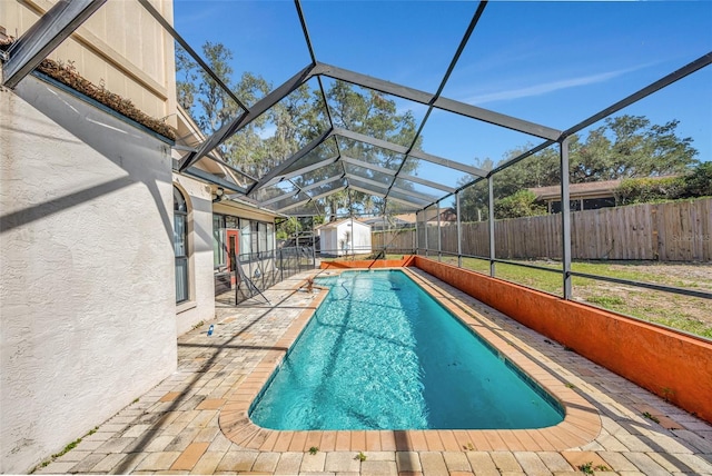 view of swimming pool featuring a storage shed, a patio, and glass enclosure