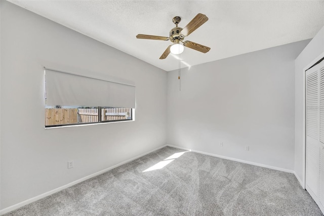 carpeted empty room with ceiling fan and a textured ceiling