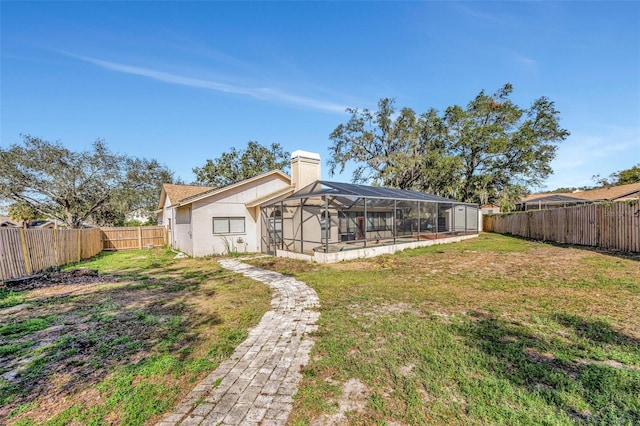 rear view of house with a yard and a lanai