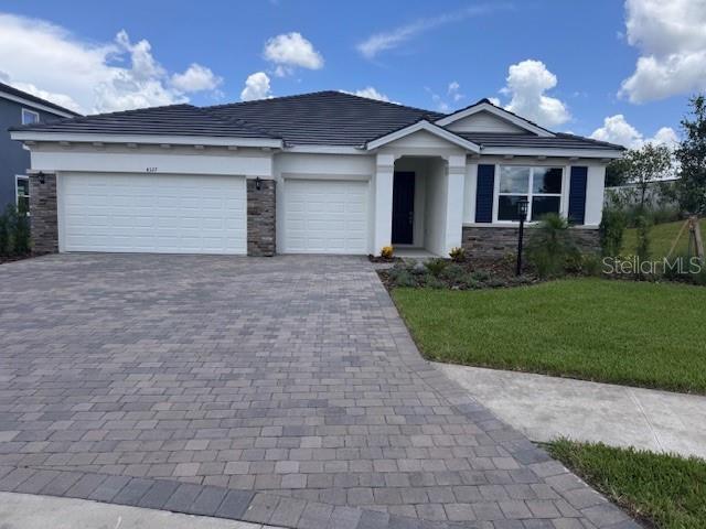 4327 Pullet Ct, Lakewood Ranch, FL 34211 - single story home featuring decorative driveway, a garage, a front lawn, stone siding, and stucco siding