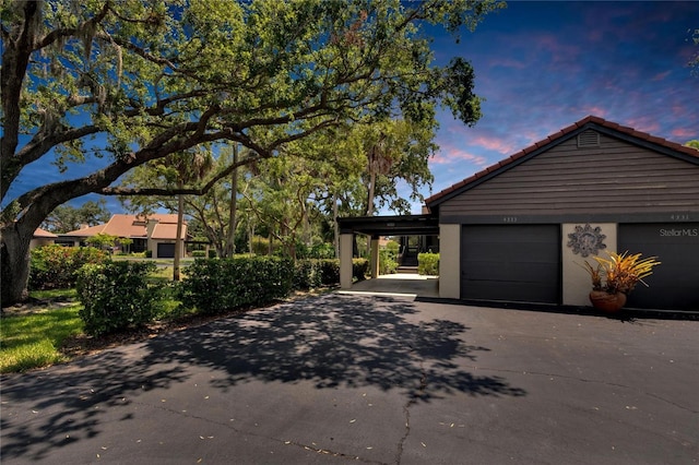 property exterior at dusk featuring a carport and a garage