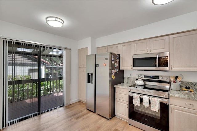 kitchen featuring light stone countertops, appliances with stainless steel finishes, and light wood-type flooring