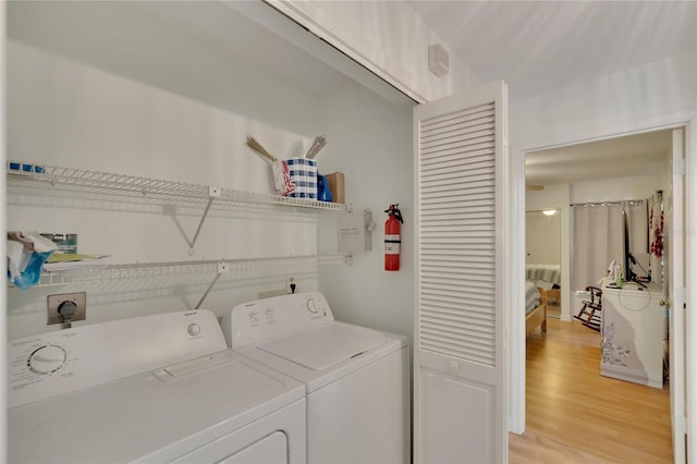 clothes washing area with light hardwood / wood-style flooring and washing machine and clothes dryer