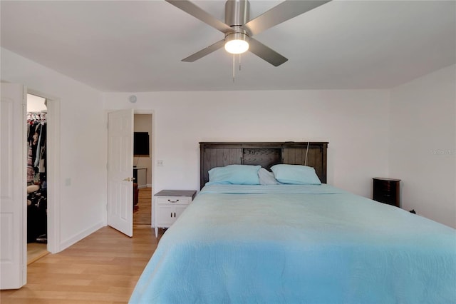 bedroom with a spacious closet, light hardwood / wood-style floors, a closet, and ceiling fan