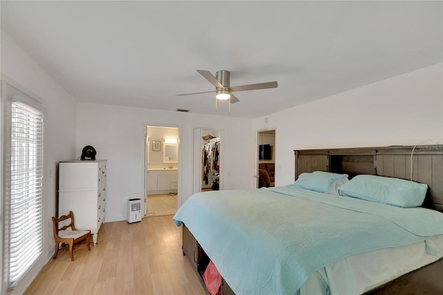 bedroom with ceiling fan, a spacious closet, a closet, and light hardwood / wood-style flooring